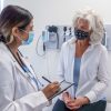 masked-senior-woman-listening-to-her-doctor-during-a-check-up-appointment